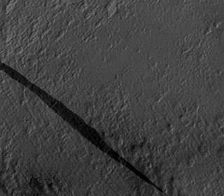 Dark slope streaks often do not affect the underlying texture of the slope on which they form, indicating that the disturbance causing the streak is superficial. Image is portion of MOC-N/A frame M09/00039, based on Sullivan et al., 2001, p. 23,612, Fig. 5a. The streak here is 1.3 km long. Mars Slope Streak M0900039.jpg