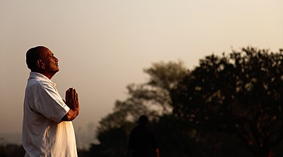 A side view of a Hindu man in namaste pose