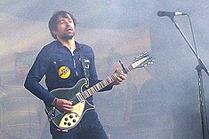 A man (Peter Morén) playing the guitar on stage.