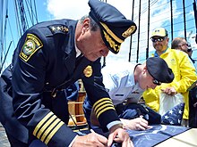Edward Deveau, chief of the Watertown Police Department in Massachusetts, signing a U.S. flag aboard the USS Constitution in 2013. Watertown police chief signs flag 130604-N-SU274-403.jpg