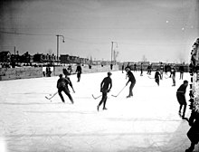 Photo en noir et blanc de jeunes hommes jouant au hockey sur glace sur une patinoire extérieure, vers 1923