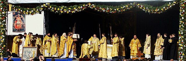 Great Entrance at an outdoor hierarchical Divine Liturgy. In the center the protodeacon with the diskos is kneeling in front of the bishop.