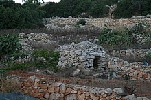 A girna in a rural area, surrounded by rubble walls Malta Tal1.jpg