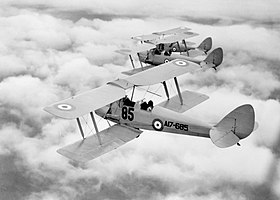 Belakang tampilan tiga perempat dari tiga pesawat yang lebih besar dalam penerbangan di atas awan