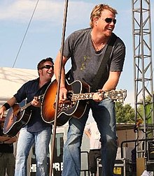 Photograph of Pat Green singing while playing an acoustic guitar