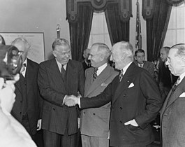 Recently sworn in George C. Marshall as the new United States Secretary of State shaking hands with his predecessor James F. Byrnes, as President Truman looks on, at the White House, 21 January 1947.