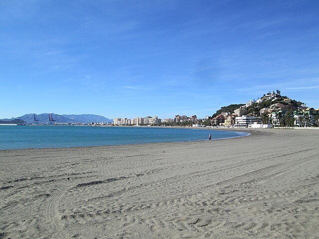 Sandy beach with the sea and Málaga port in the distance.