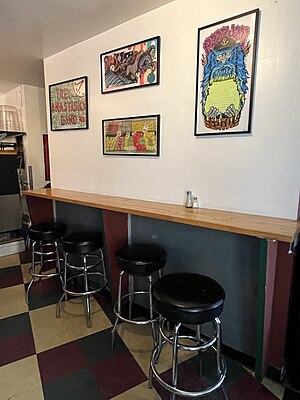 Photograph of a building interior with four stools at a bar