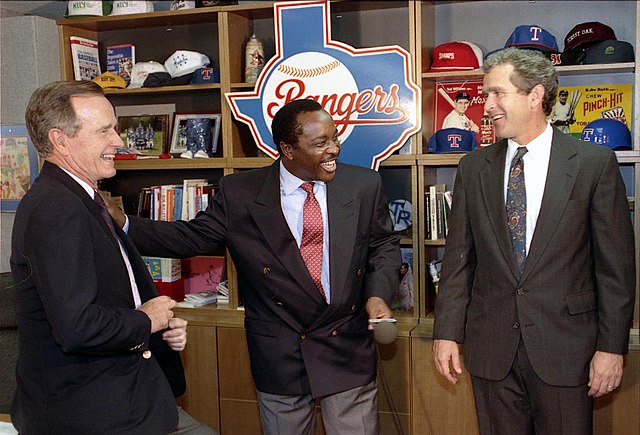 President George H. W. Bush with son, George W. Bush, and baseball broadcaster, Joe Morgan, in the Texas Rangers locker room, 1991. Future president G
