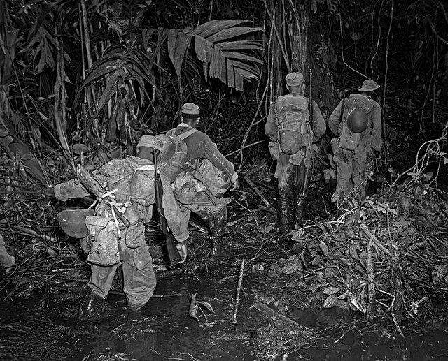 En route to Hill 165, members of 93rd Div. struggle through some clinging mud along the East-West trail on an island in the South Pacific. April 15, 1