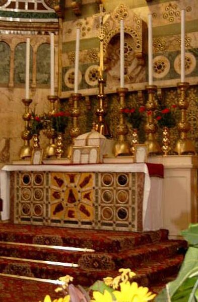 A pre-1969 Roman-Rite high altar decorated with reredos and set on a three-step platform, below which the Prayers at the Foot of the Altar are said. L