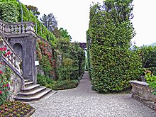 Transverse view along a narrow terrace, Villa Carlotta on Lake Como, Tremezzo, Italy: stairs from an upper level are inset into the retaining wall. Villa Carlotta Terrasse.jpg