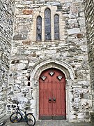 Церковь Восс (Voss kirke-kyrkje, Vangskyrkja) Каменная церковь 13-го века, Восс, Норвегия 2016-10-25-05- портал входной двери, каменная стена, витраж. Jpg