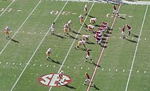 Giocatori di football americano in formazione su un campo verde.