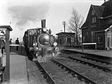 Stoomlocomotief nr. 7008 (serie 7000) van de NS met rijtuigen langs het perron van het station Bovenkerk.