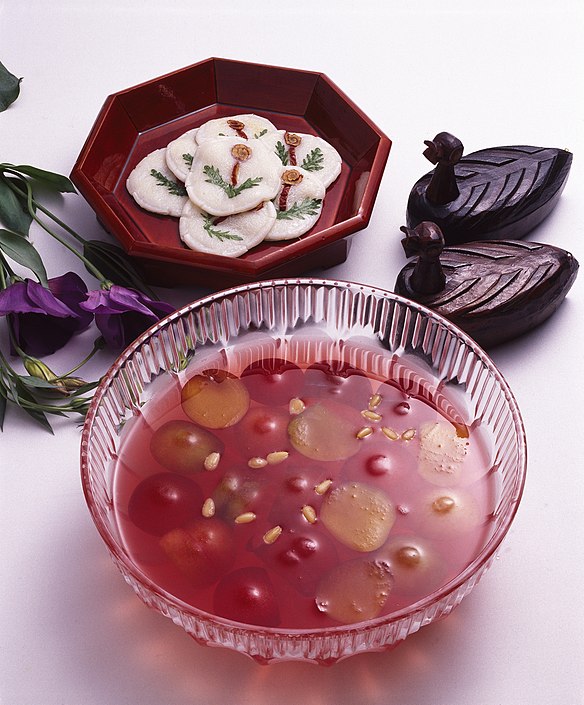 A glass bowl of grape hwachae and some hwajeons on lacquered octagon plate