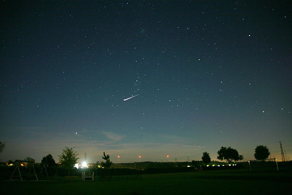 Light sources of different magnitudes. A very bright satellite flare can be seen in the night sky.