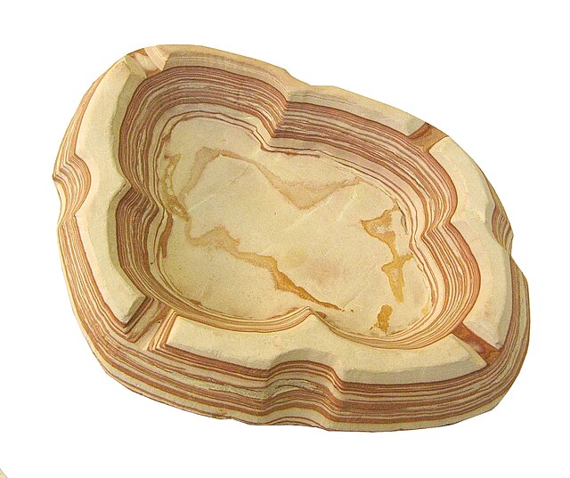 An ashtray carved out of a soft form of banded ironstone. Note the alternating red and beige layers that make up this rock. The red layers much richer