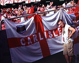 Clarke on photographic assignment in front of Carlisle flag at an England football match abroad in 2004 STUART Carlisle England flag 6911.jpg