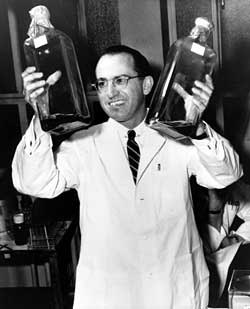 Jonas Salk in 1955 holds bottles of a culture used to grow polio vaccines