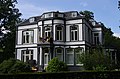 Statige neoclassicistische villa met onregelmatig verloop in fraaie tuin.