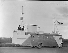 Royal Navy officers 'aboard' 'HMS SPURIOUS MARK II' - a bus converted to resemble the island of an aircraft carrier. The bus is being driven along a runway or taxi way at Royal Naval Air Station East Haven at Carnoustie, Scotland. The Royal Navy during the Second World War A24702.jpg