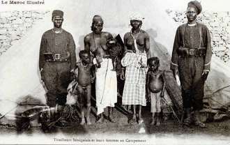 Foto af to sorte soldater med deres koner og børn foran et telt
