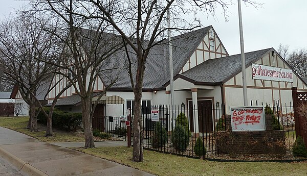 The headquarters of the Westboro Baptist Church with the sign "godhatesamerica.com". The graffiti on the sign reads "God Hates The Phelps".