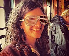 A young woman smiles while wearing Shutter shades.