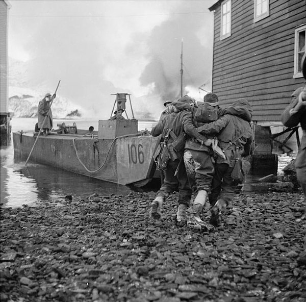 A wounded soldier is helped onto an LCA.