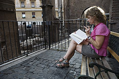 A young woman reading sitting on a bench in the Forum, near the Teatro di Marcello, Rome, Italy