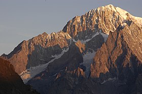 Le mont Blanc de Courmayeur au lever du soleil depuis l'est avec la pointe Innomée éclairée au centre, encadrée par l'arête du Brouillard à gauche et les aiguilles de Peuterey à droite.