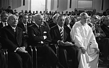 Max Tau (left) at the ceremony for Friedenspreis des Deutschen Buchhandels for Frère Roger (in white) in St. Paul's Church, Frankfurt am Main 1974. West-German president Walter Scheel is seated next to Tau. Credit: Deutsche Bundearchiv