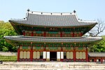 Two storied traditional building with tile roof and walls decorated in red, green and yellow.