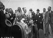 Photo d'Achille Varzi et Louis Chiron derrière le volant d'une Bugatti Type 51, entouré des officiels du Grand Prix de France 1931.