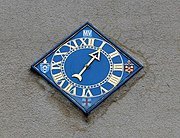 時計のダイヤル。細かな目盛と時刻を示すI～XIIの文字が刻んであり、針がひとつだけの素朴なもの。