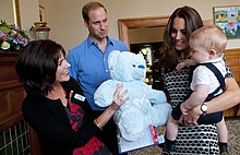 Prince George is presented with a Plunket bear during a Plunket group at Government House, Wellington, in 2014, while the Duke and Duchess of Cambridge look on Duke and Duchess of Cambridge Plunket group 2014.jpg