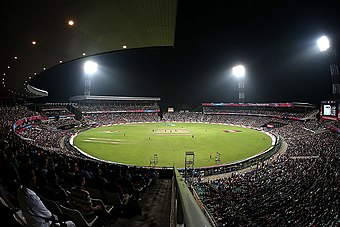 Eden Gardens under flood lights packed with spectators during a match.