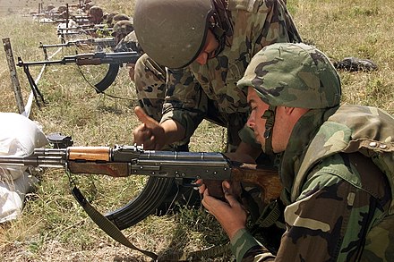 A Romanian soldier instructing a U.S. Marine in clearing a RPK