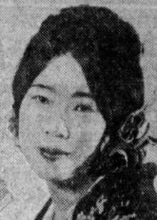 A young Japanese woman, smiling, with dark hair center parted and dressed back to the nape.