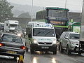 Isle of Wight Ambulance Service BU08 JHO, a Vauxhall ambulance, in Staplers Road, Newport, Isle of Wight, seen passing traffic in heavy rain. Traffic congestion was incredibly heavy during the Isle of Wight Festival 2012, where waterlogged grounds were causing a nightmare in getting vehicles on site.