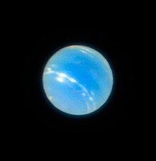Neptune en bleu très clair devant un fond noir, des nuages sont visibles.