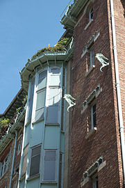 Photo en couleur et en contre-plongée d'une façade en brique avec une sorte de demie-tour en métal avec ouvertures rectangulaires en escalier