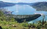 Foto von einer Anhöhe auf eine an einem Fjord gelegenen Stadt hinunter