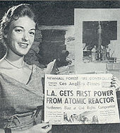 Gail Fowler of Atomics International displays an L.A. Times headline about the reactor's production of electricity (November 1957) SRE News 1957.jpg