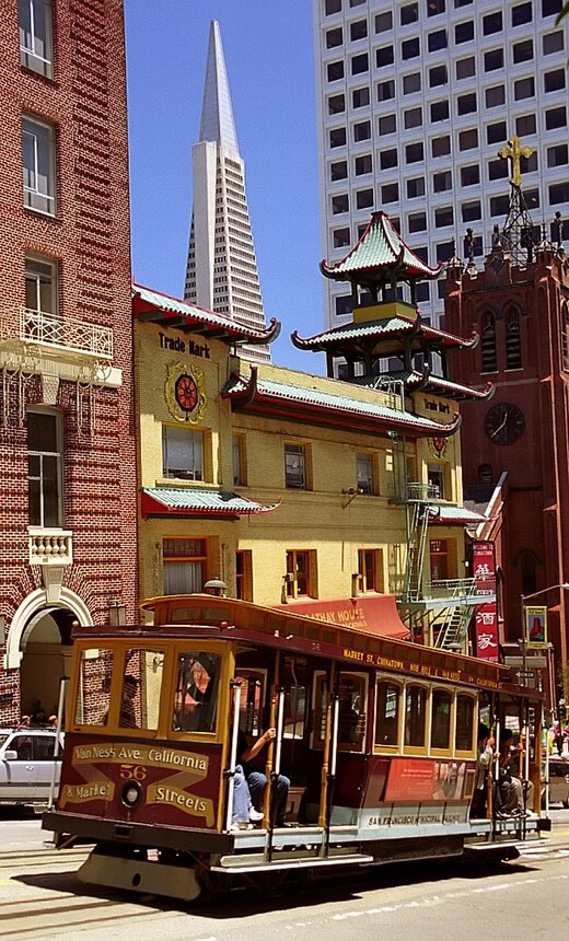 Cable Car 56 ascends Nob Hill from Chinatown along California Street; prominent buildings shown include the Transamerica Pyramid, Sing Chong Bazaar, Hartford Building, and Old Saint Mary's Cathedral.