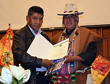 Pedro Montes and an indigenous leader jointly hold up a certificate of recognition.