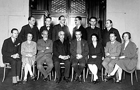 monochromes Foto von acht sitzenden Personen, hinter denen eine Reihe von sechs Personen steht