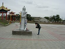 A Kalmyk woman praying in front of the statue before entering the temple