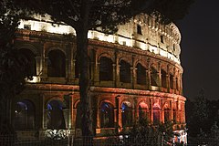 The Colosseum at night, lit in colored lights, Rome, Italy